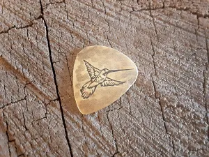 Guitar pick in brass with hummingbird