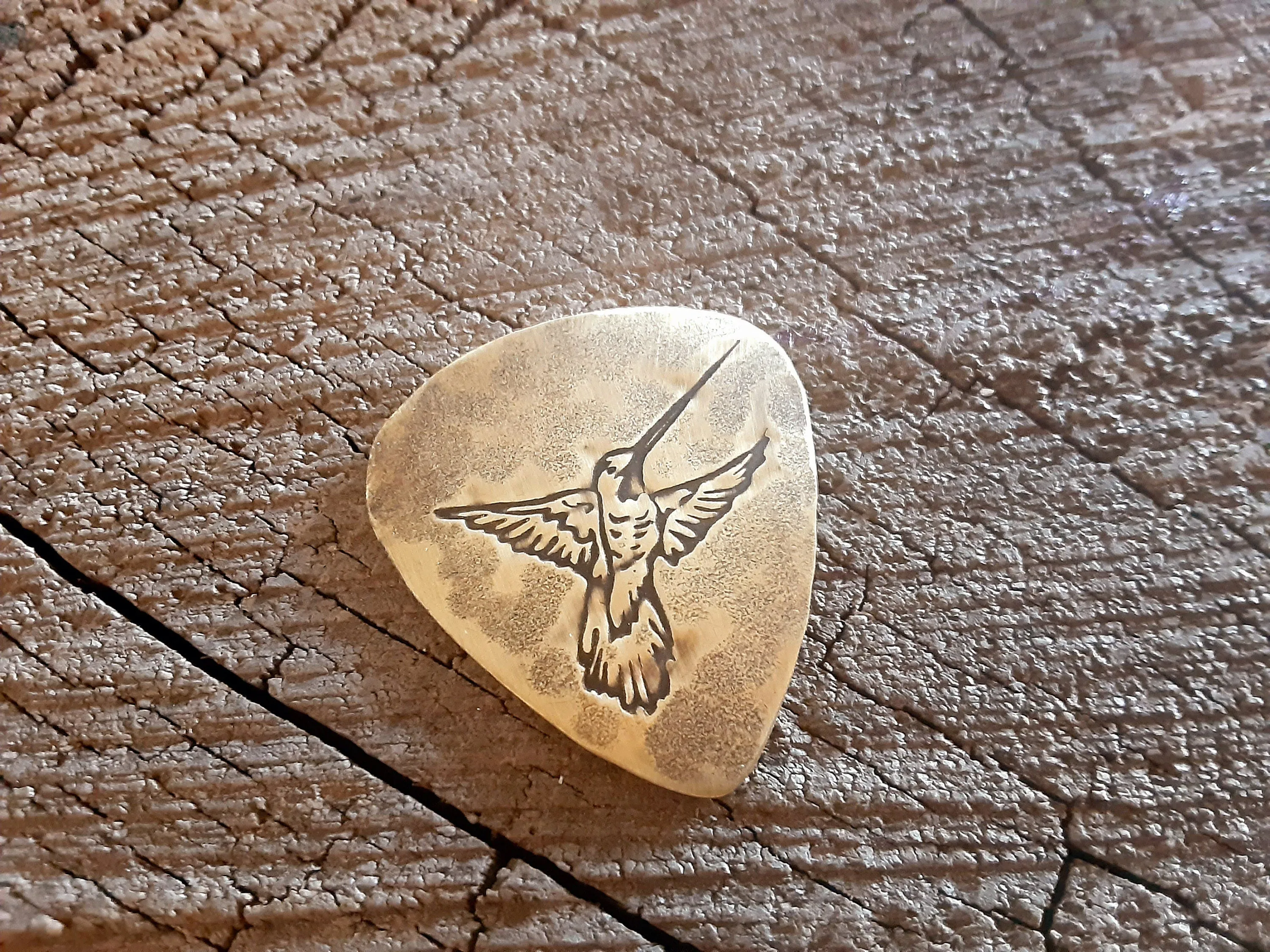 Guitar pick in brass with hummingbird
