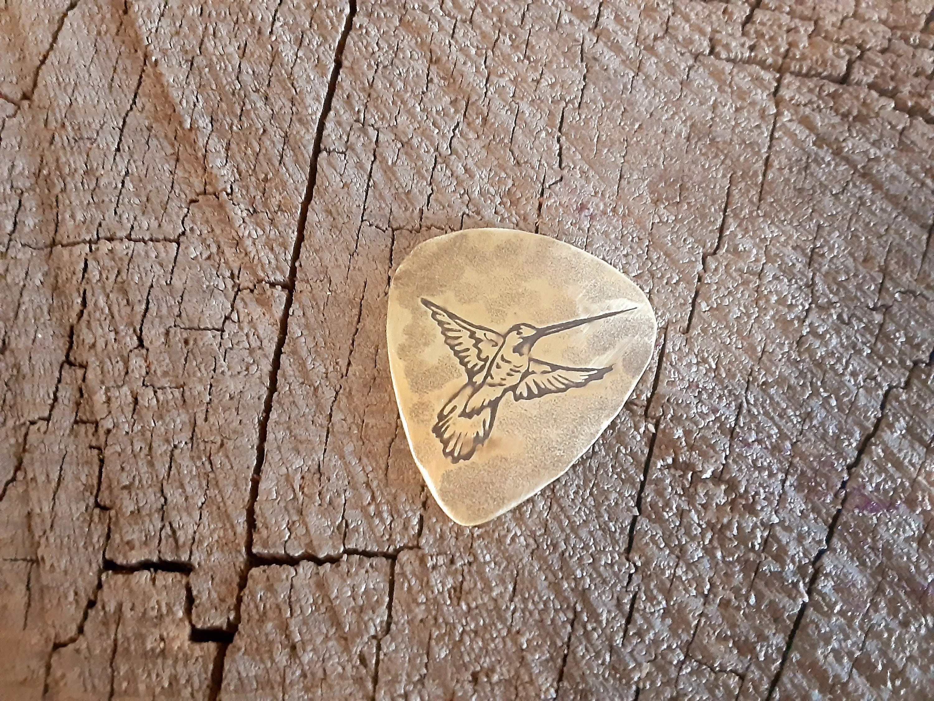 Guitar pick in brass with hummingbird